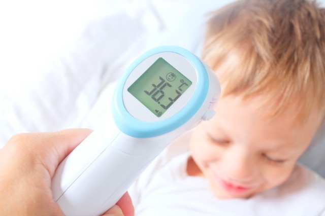 Kleinkind, dessen Temperatur mit Infrarot Fieberthermometer gemessen wird
